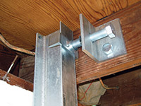 Securing the i-beam system to the top of the floor joist in a foundation wall repair in Big Lake.