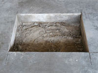 Creating the hole in the garage slab floor during the wall anchor installation in Hoonah.