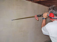 Drilling the hole in the foundation wall for street creep repairs in Gakona